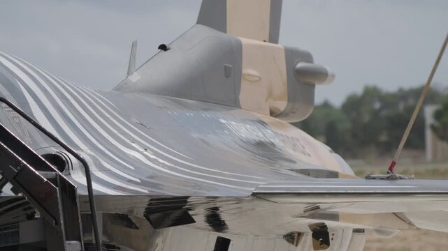 Man in black uniform standing on aircraft tail while cleaning horizontal stabilizer with mop