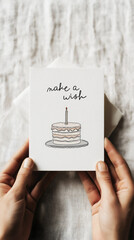 Minimalist birthday card held in hands, simple line drawing of a layered cake with a single candle, make a wish text. 