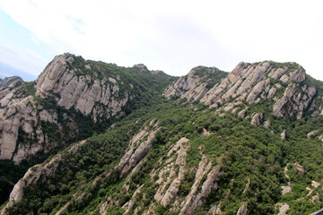 Naklejka premium Rocky peaks of Montserrat with historic chapels and churches perched among the cliffs, in Catalonia, Spain, taken in July 2024.