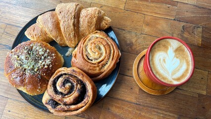 Coffee and Pastry Combo with Fresh Latte Art and Assorted Baked Goods on Rustic Wooden Table