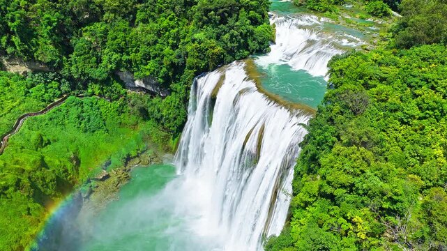 The famous Huangguoshu Waterfall natural landscape in Guizhou, China. Aerial shot of a magnificent large waterfall cascading down into a turquoise pool surrounded by lush green tropical forest in summ