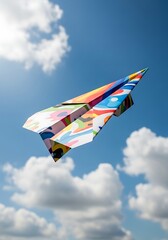 Colorful folded paper aircraft soars through bright blue sky with white clouds