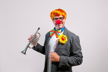 Clown man in an orange wig playing a trumpet