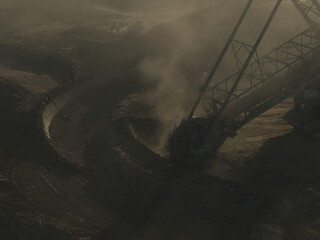 Naklejka premium High resolution panoramic view of massive mining machines in an open pit coal mine, surrounded by dust. Powerful industrial scene showing large scale extraction, energy production, and human impact.