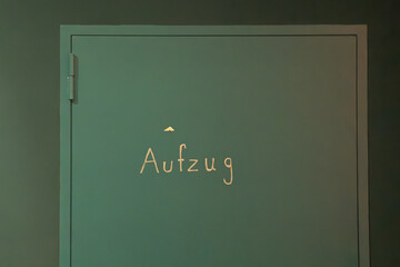 Schriftzug Aufzug auf einer gr&uuml;ner T&uuml;r in einer gr&uuml;ner Wand