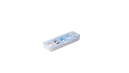 Closeup of a small pill organizer on a white surface near an office desk symbolizing medication management for migraineinduced nausea in a professional setting.