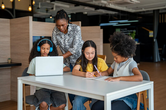 African school teacher is teaching and guiding group of young student in the class using information from experience and internet for academic literacy study and education