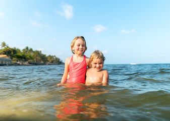 Happy siblings enjoying a warm sea during their exotic vacation in Kenya. The children are playing and relaxing in ocean water, expressing joy, freedom, and carefree holiday moments.