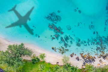 Aerial view of shadow passenger plane silhouette and sandy beach blue sea with waves at sea beach summer vacation sea travel concept	