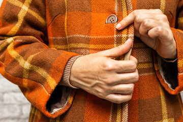  A woman buttoning her coat, close-up. A woman unbuttons her coat. women's fingers fastening a button. woman putting on coat. fingers fasten a button. 
