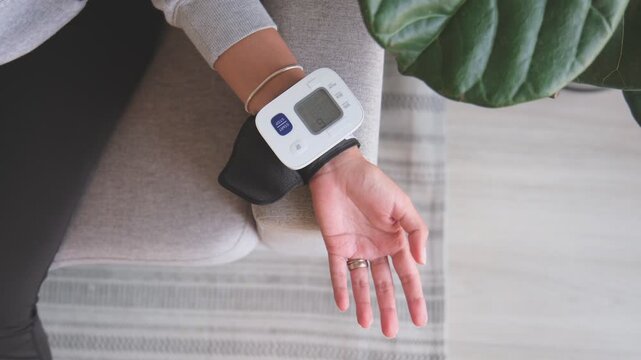 Woman monitoring her blood pressure at home with a digital wrist cuff
