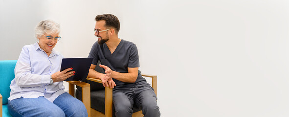 Senior woman discussing her medical records with male doctor during hospital visit for consultation in waiting room