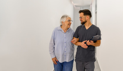 Elderly woman walking arm in arm with male ophthalmologist during health discussion in hospital corridor