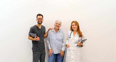 Portrait of doctor colleagues holding laptops and standing with elderly patient against white background