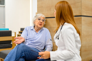 Senior woman in eyeglasses explaining her medical symptoms to female doctor in hospital during routine checkup