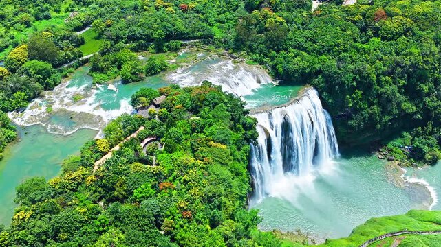 The famous Huangguoshu Waterfall natural landscape in Guizhou, China. Aerial shot of a majestic waterfall cascading into a green lake surrounded by lush forest in summer.