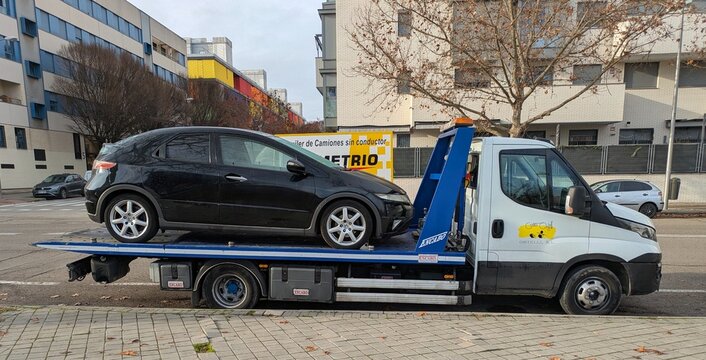 Gr&uacute;a con veh&iacute;culo averiado en la plataforma, delante de un taller mec&aacute;nico en Madrid, Espa&ntilde;a, 1 de enero de 2026