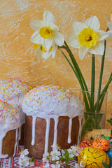 festive Easter composition, Easter egg with white icing dripping, Festive still life with Easter cakes and Easter eggs and a bouquet of white daffodils on the table