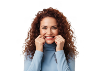 Young woman with curly hair and blue turtleneck smiling and looking directly at the camera with her hands near her face isolated on transparent background