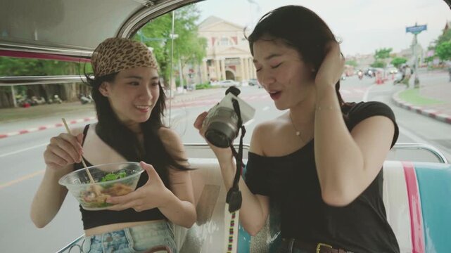 Two young woman sisters sitting tuk tuk taxi local tour hanging out trip gen Z hipster travel in Bangkok, Thailand