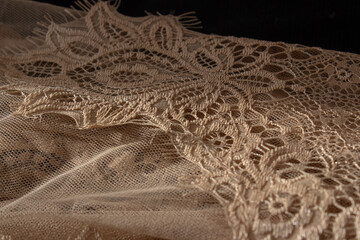 Close-up of golden beige lace trim with intricate floral details, soft focused perspective of...