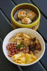 Chicken and mushroom rice porridge with creamy smooth texture, savory toppings, crunchy crackers, peanuts, herbs, and warm comforting flavor, modern Asian breakfast dish with clean appetizing presenta