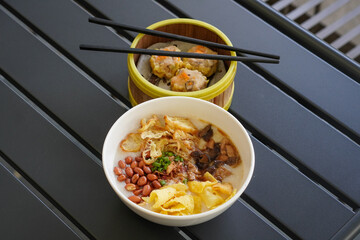 Chicken and mushroom rice porridge with creamy smooth texture, savory toppings, crunchy crackers, peanuts, herbs, and warm comforting flavor, modern Asian breakfast dish with clean appetizing presenta