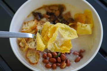 Chicken and mushroom rice porridge with creamy smooth texture, savory toppings, crunchy crackers, peanuts, herbs, and warm comforting flavor, modern Asian breakfast dish with clean appetizing presenta