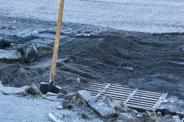 Working shovel,storm drain grate before removal during road repairs