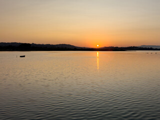 Obraz premium Warm golden sunset over Chalkiopoulos Lagoon near Corfu Airport, Greece. Calm water reflecting the sun, summer evening