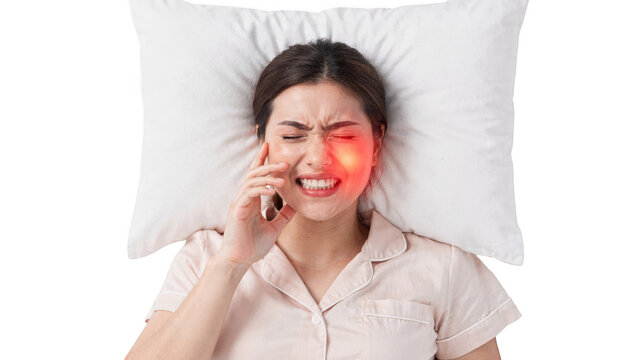 Overhead view of a female resting on white bedding with a visible jaw clench illuminated cheek area symbolizing teeth grinding pain set against a clean white backdrop.