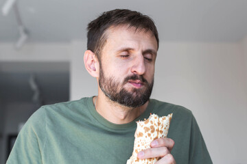 Man enjoying wrap food with closed eyes feeling pleasure and satisfaction at home concept of comfort casual lifestyle authentic real everyday moment