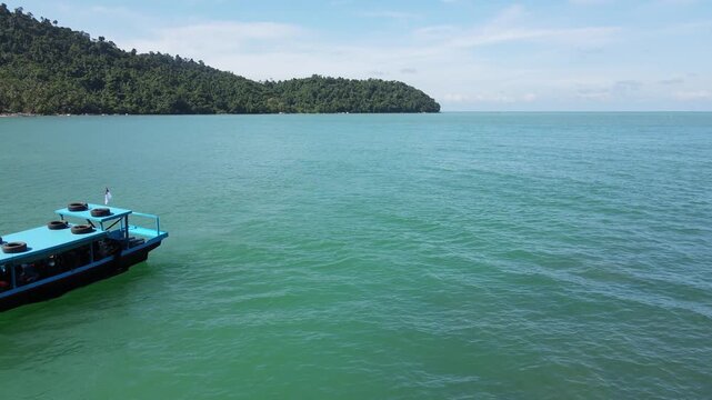 Drone aerial view of small boat cruising calm tropical sea coast scene