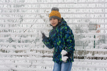Close up outdoor winter portrait of boy playing snowballs.