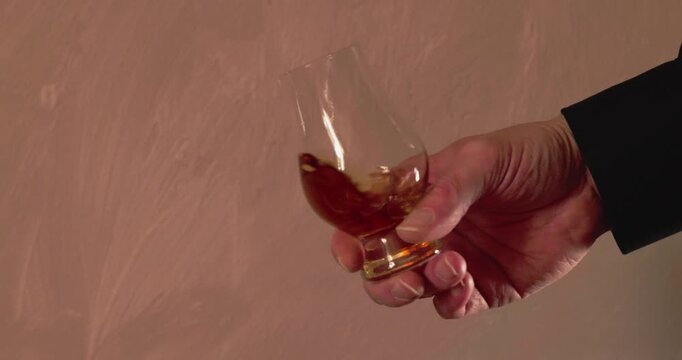 Eine m&auml;nnliche Hand schwenkt ein Glas w&auml;hrend einer Whiskeyverkostung
.