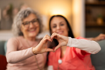 Home Caregiver And Senior Woman Making A Heart With Their Hands