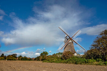 Oldsumer Windm&uuml;hle mit Wolkenhimmel und abgeerntetem Feld im Vordergrund auf der Nordseeinsel F&ouml;hr