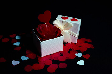 Open and closed gift box with satin ribbon, red and white heart petals on black background for Valentine's Day