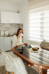Business woman drinking coffee while working using laptop computer at home