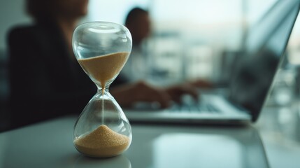 Hourglass on Office Desk with Blurred Business People Working in Background, Time Concept