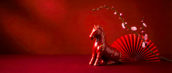 card with a Chinese horse figure on a bright red background and a branch of plum blossoms, copy space, with Chinese New Year greetings