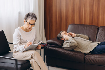 Psychologist writing notes during therapy session with patient
