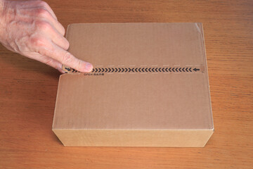Hand opening a parcel from China labeled &ldquo;OPEN&rdquo; in both English and Chinese characters, symbolizing international trade, the import and export of Chinese goods, global logistics, and e-commerce.