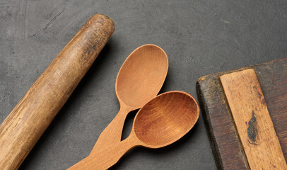Wooden spoons, cutting board and rolling pin on a dark surface