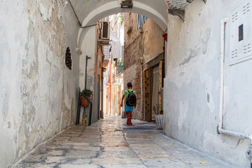 Elementary school student walking through a narrow historic alleyway