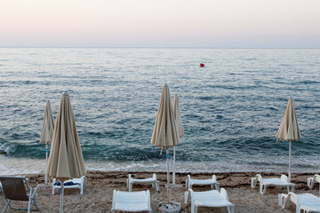 Empty beach with closed umbrellas at dusk
