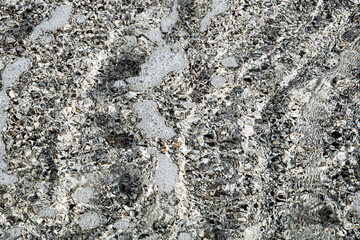 Foamy seawater over pebbly beach surface