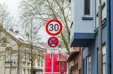 German traffic signs indicating a 30 km/h speed limit and school bus zone