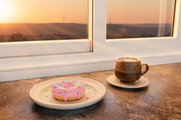 Donut und eine Tasse Kaffee vor einem Fenster im Morgenlicht, im Hintergrund der Stuttgarter Fernsehturm im warmen Gegenlicht © createyour.photo