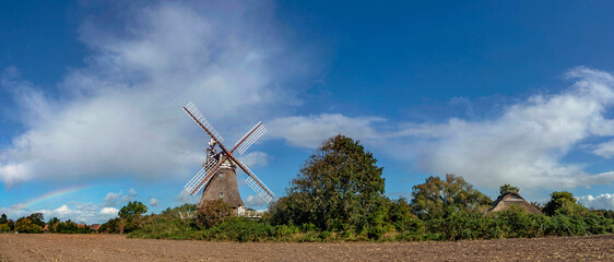 Panoramafoto der Oldsumer Windm&uuml;hle mit Wolkenhimmel und abgeerntetem Feld im Vordergrund auf der Nordseeinsel F&ouml;hr
